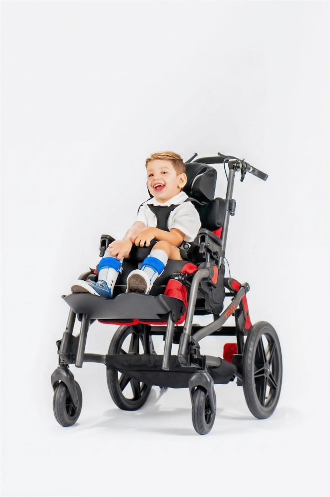 Criança sentada no carrinho postural infantil Leggero Trak vermelho